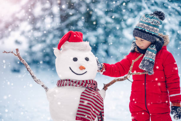istock Small smiling child building a cute snowman. 1436500844
