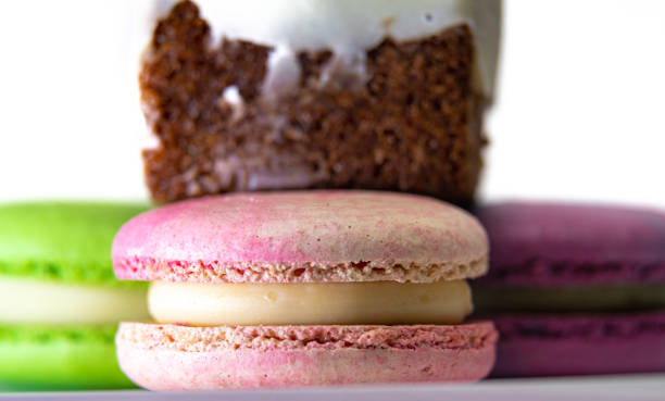 deliziosi macarons francesi colorati, con un pezzo di torta, su uno sfondo bianco - biscotti cookie chocolate pistachio foto e immagini stock
