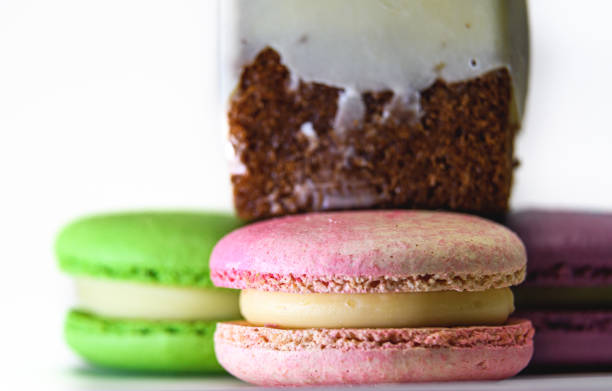 deliziosi macarons francesi colorati, con un pezzo di torta, su uno sfondo bianco - biscotti cookie chocolate pistachio foto e immagini stock