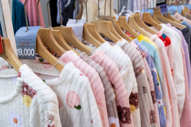 服、パジャマ、ローブでいっぱいのショッピングランク。販売のための異なる色の服の束。チープ服とファストファッションのテーマ