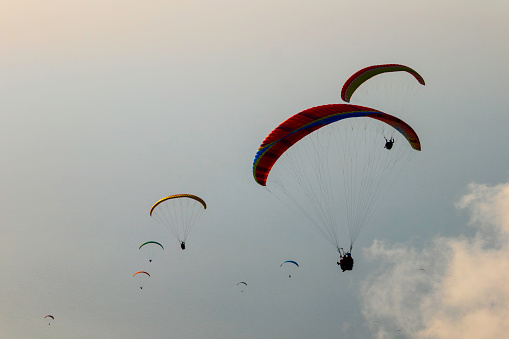 Many paraglider at sunset over the sea among the clouds