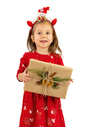 Happy girl holding a gift box in hands isolated on white background. A blond girl is delighted with the Christmas present she has received. The cute child is surprised and delighted with the present.
