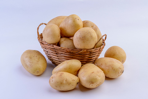 Potatoes inside straw basket isolated on white background.