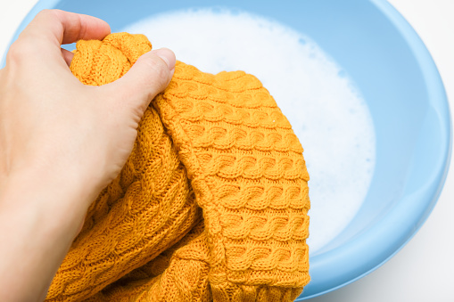 Hand washing of delicate woolen knitted clothes, sweaters concept, care of bright color clothes.