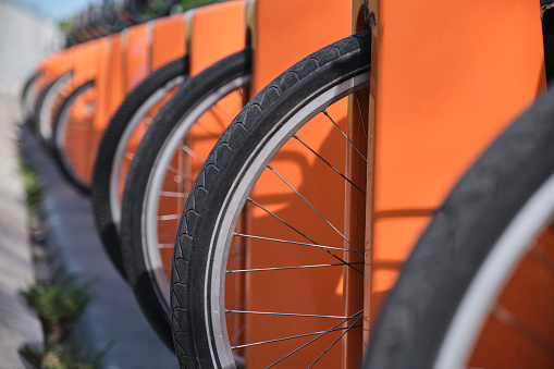 Row of bikes at a bicycle rental station. Ecological and sustainable urban mobility concept. Close-up image of the tires, composition with copy space.