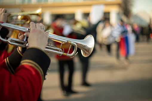 Orchestra with wind instruments. Trumpeters in ceremonial uniforms. Red military clothing. Musicians on street.