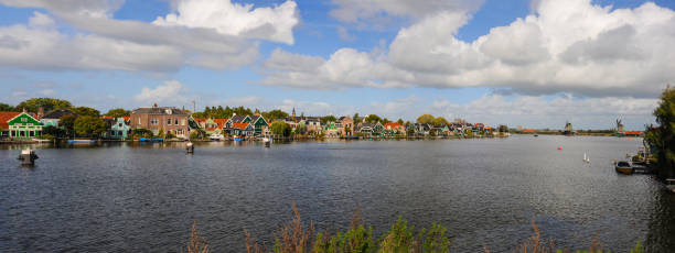 A Panoramic view of Zaandam Schans and a row of old world Dutch architecture homes along the river. stock photo