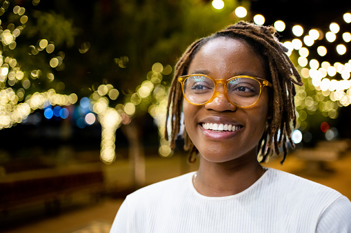 Beautiful African-American Woman in Her Twenties in a Park in El Paso Texas Under Decorative Lighting Interacting on a Laptop on a Conference Call