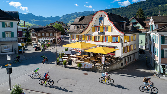 Appenzell, Switzerland - June 24, 2022: Adler Hotel - Host of the Black Eagle, Is one of the many colorful hotels in the center of town. Appenzell is famous for cheese and beer and a popular destination to hike the Alpstein region. Children ridding bicycles to school in the morning