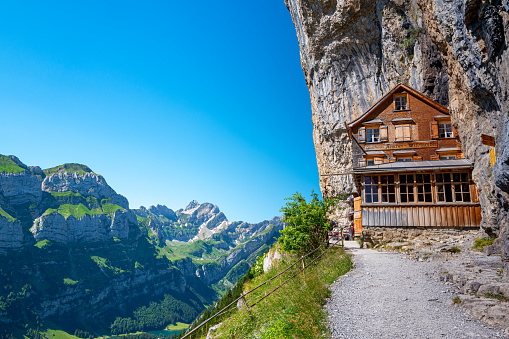 Ebenalp, Switzerland - June 26, 2022 : Famous Swiss Alps Gasthaus Aescher -Wildkirchli under the Ascher cliff viewed from mountain Ebenalp in the Appenzell region in Switzerland