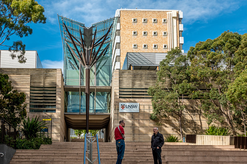 Sydney, Australia - May 20, 2021: Steps to Tree of Knowledge architectural structure of The John Niland Scientia Building at the University of New South Wales. UNSW plaque on wall; two men conferring.