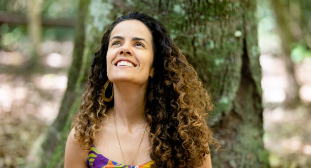 Smiling young woman looking up at the treetops in a forest
