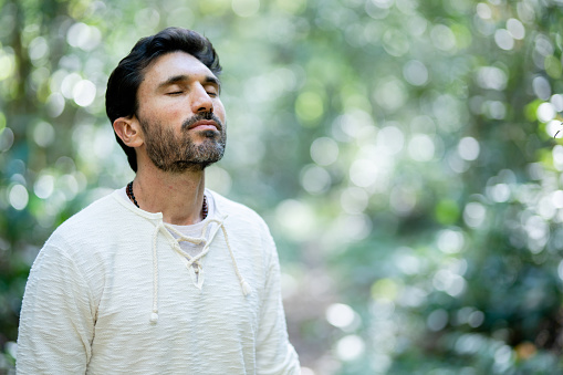 Man taking deep relaxing breath of fresh air during a walk alone in a forest in summer