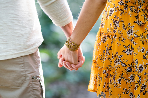 Close-up of an affectionate couple holding each other's hands while standing together outside in summer