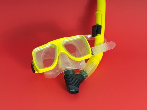 Yellow snorkel and mask centered on a red background.