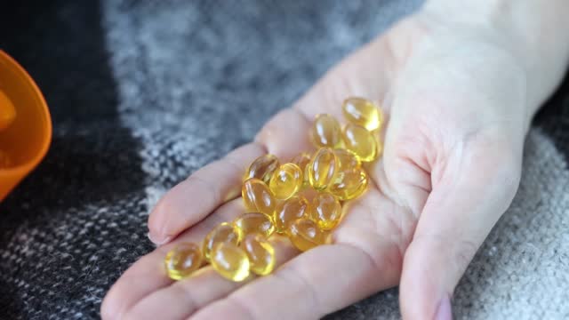 Gold capsules are poured from jar onto hand