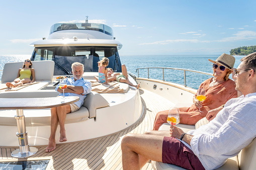 Multigenerational family enjoying cruise on impressive yacht on sunny day. Spending time on front deck. Luxury vacation at sea.