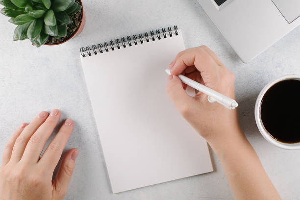 istock Womans hands writing to do list or plans in notebook on office desk. Top view, copy space 1436563662