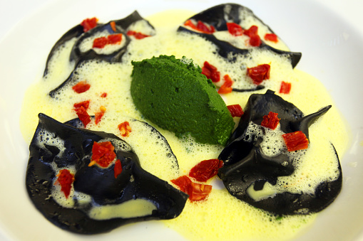 Black Squid Ink Ravioli with sauce on the dinner plate.