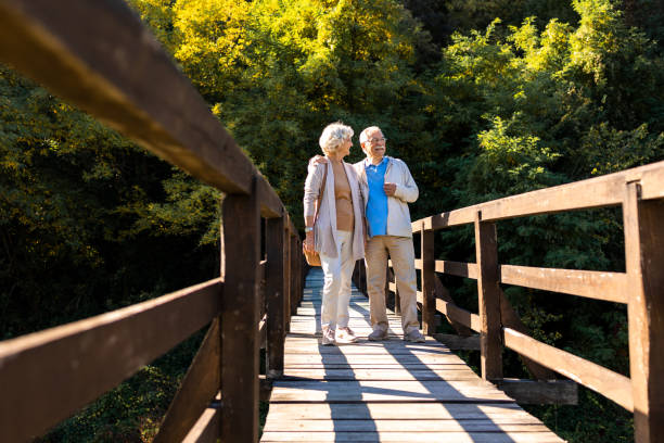 счастливые пожилые люди наслаждаются прогулкой на природе - couple autumn embracing bridge стоковые фото и изображения