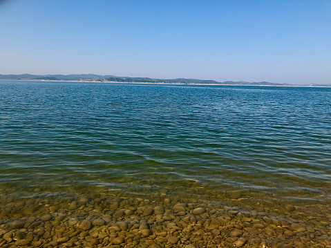 Beautiful beach water. Pebbles seen in clear calm water