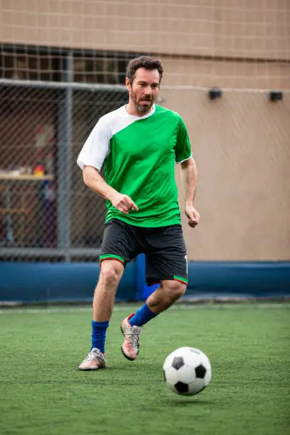 Wide view of amateur male sports fan playing soccer on field during daytime