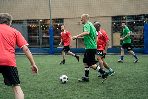 Wide view of amateur sport fans playing football at urban football pitch during daytime