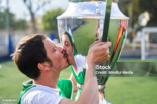 Male Amateur Soccer Player Kissing Big Trophy Cup After Winning Tournament Stock Photo - Download Image Now