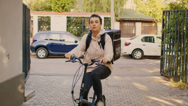 istock Female restaurant worker going to people front door and delivering meal 1436602100