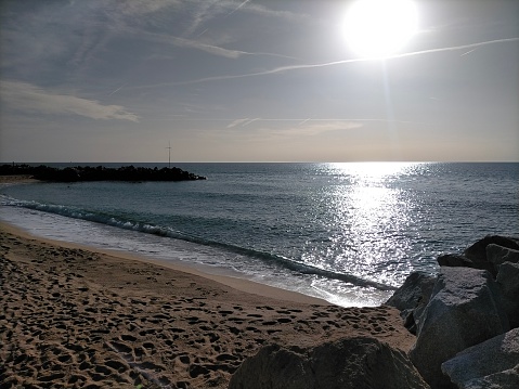 Escena de la playa de Vilassar de Mar con el sol de la madrugada y el reflejo de la luz del sol en el mar en calma. photo
