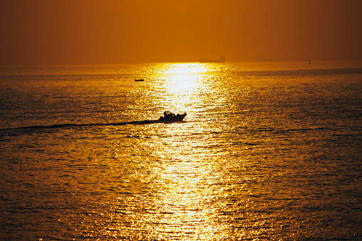 Sunrise in the sea and fisherman goes to fishing on boat
