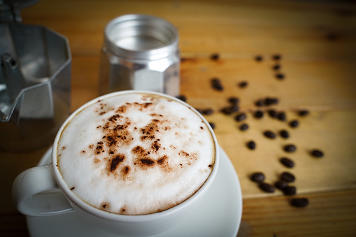 Hot cappuccino in white cup with wooden background,coffee is a popular drink all over the world.