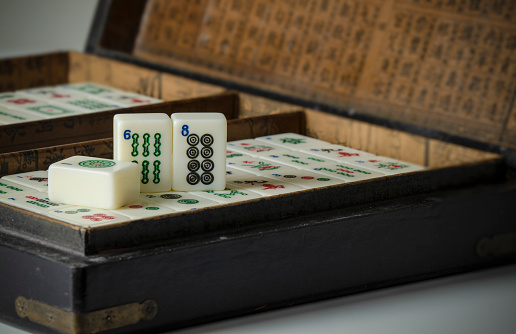 Pieces of mahjong in box on white table