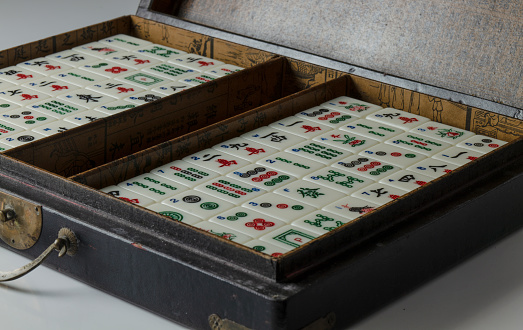 Pieces of mahjong in box on white table