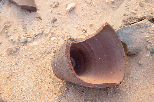 broken clay vase lies on the sand