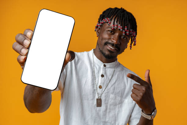 istock Excited young african man holding smartphone with white blank screen in hand on yellow studio background 1436616971