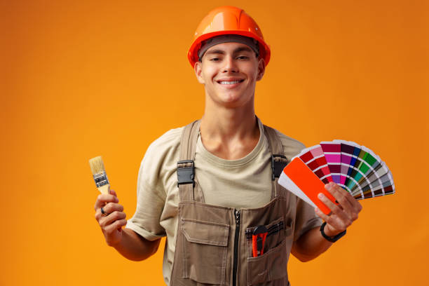 istock Handsome young worker in uniform holding paint samples palette on yellow background 1436620237