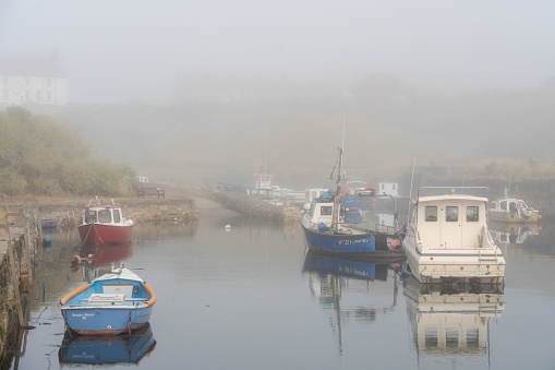 Seaton Sluice, United Kingdom – August 14, 2022: Boats in heavy sea fret at the harbour, at high tide in Seaton Sluice, Northumberland, UK.