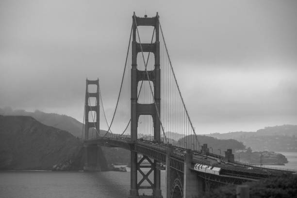 graustufenaufnahme der berühmten golden gate bridge in san francisco im sommer mit nebel bedeckt - golden gate bridge bridge weather california stock-fotos und bilder