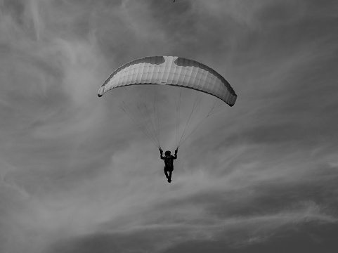 Val Andre, France – August 08, 2022: A black and white of a paraglider flying in the sky.