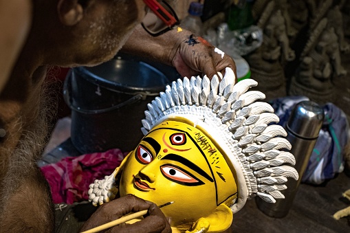 Kolkata, India – September 05, 2022: A closeup shot of a man painting the face of Goddess Durga in preparations for the Durga Puja festival