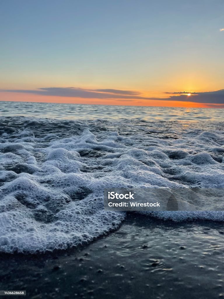 Vertical shot of sea waves with the beautiful sunset in the background A vertical shot of sea waves with the beautiful sunset in the background Architecture Stock Photo