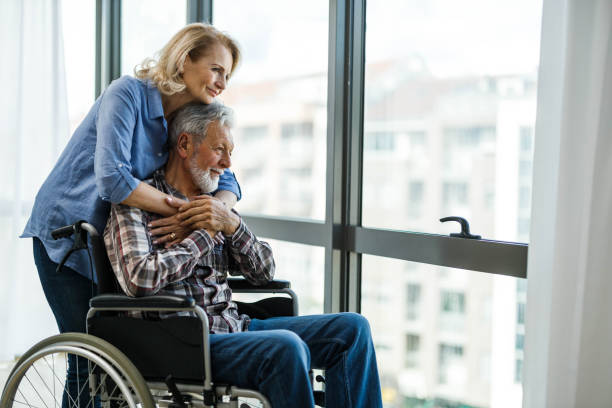 istock Mature woman and her disabled husband looking through window. 1436630036
