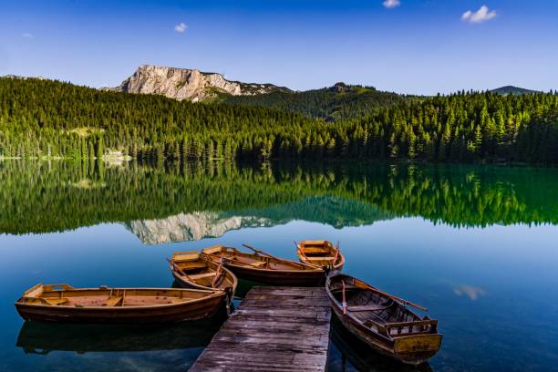 toma de un lago negro con el foco de barcos con el fondo de la montaña dormitorio en montenegro - balcanes fotografías e imágenes de stock