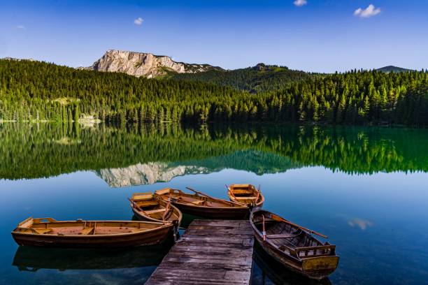 Shot of a Black lake with the focus of boats with the Dormitory mountain background in Montenegro A shot of a Black lake with the focus of boats with the Dormitory mountain background in Montenegro balkans stock pictures, royalty-free photos & images