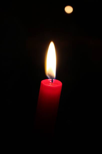istock Vertical shot of a red candle burning on a black background 1436634095