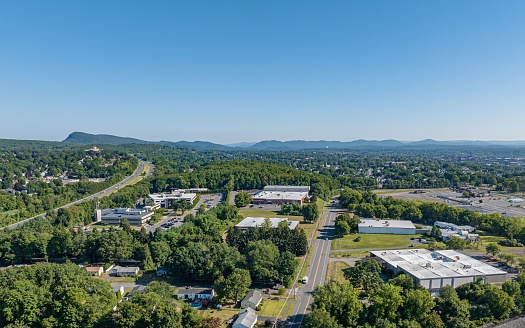 A drone shot of cityscape view, houses, road, greenery and a mount in the background