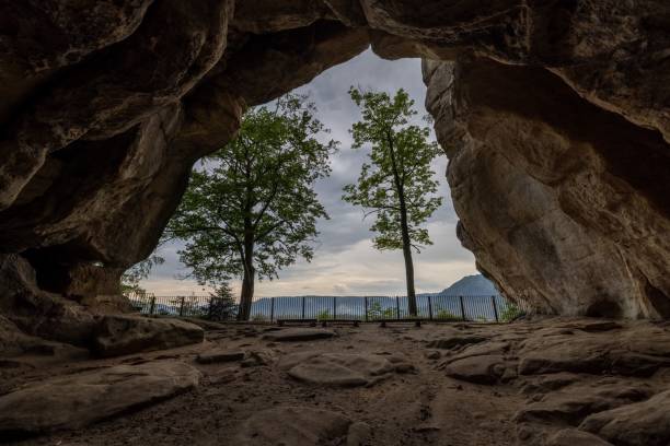 istock Green trees visible through the arch of a cave 1436635315