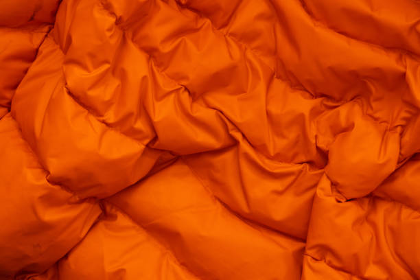 orange fabric of a warm puffed jacket as a background close-up stock photo