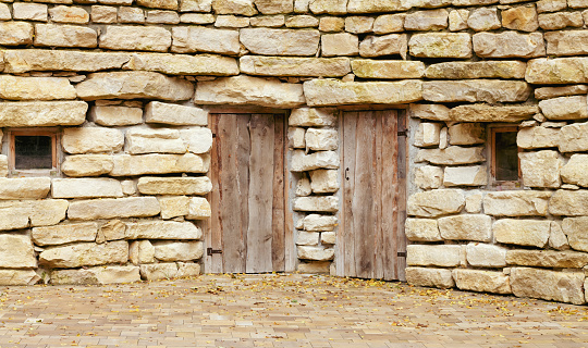 Two closed ancient wooden doors in rough stone wall